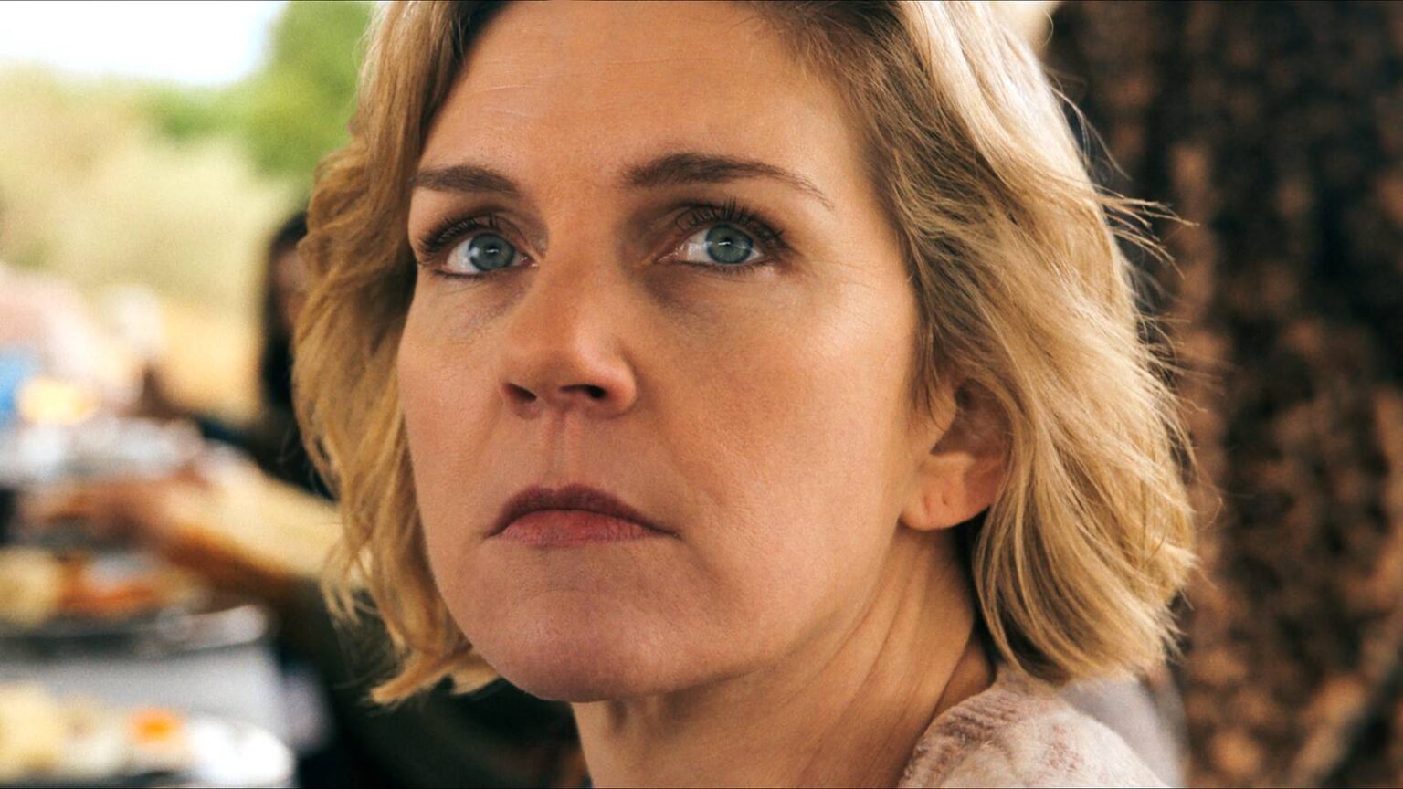 Rhea seehorn s carol looking seriously over her shoulder in pluribus.jpg