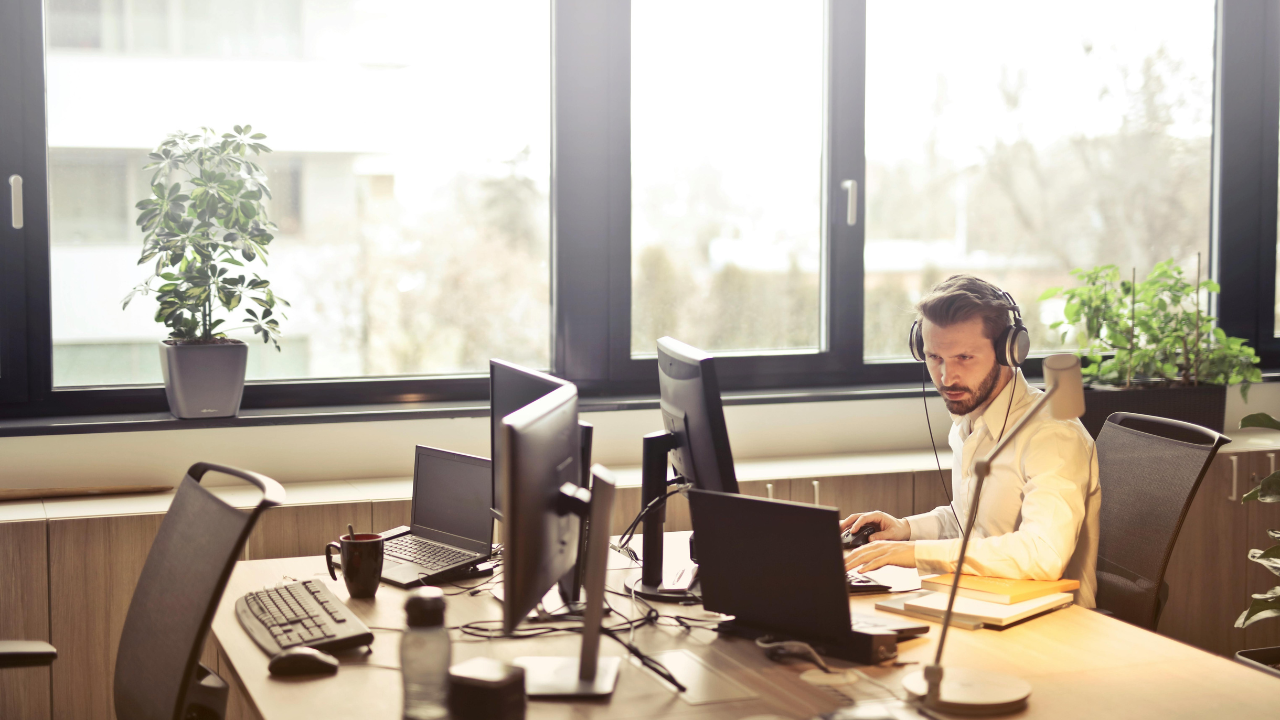 Man with headphones facing computer monitor.png