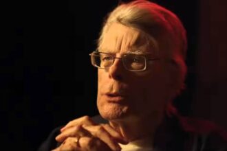 Stephen king talks with his hands clasped together.jpg