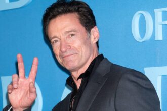 Hugh jackman makes a peace sign at the red carpet of the death of robin hood.jpg